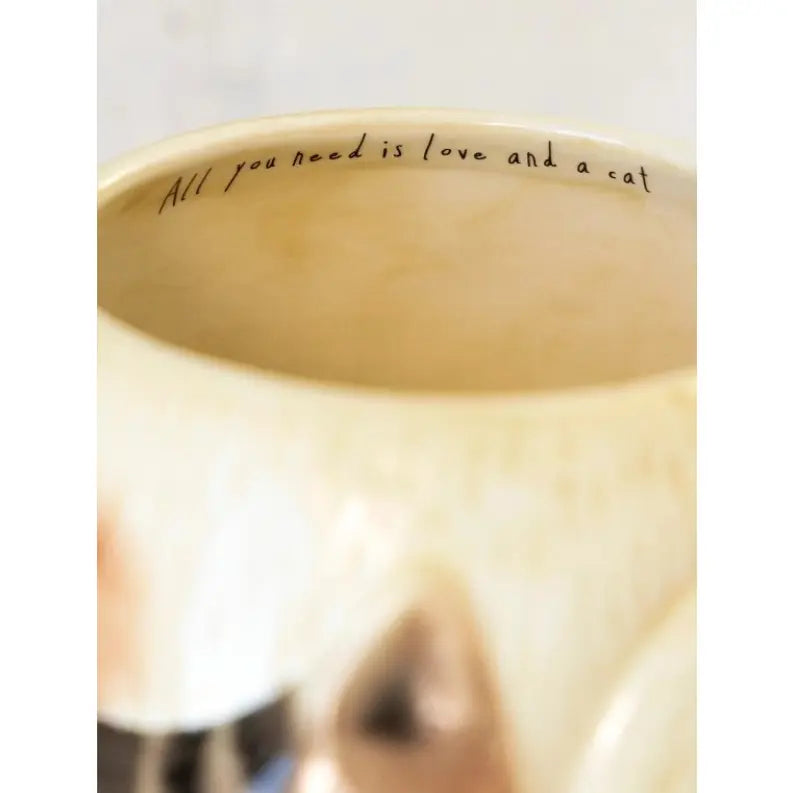 Inside rim of cream cat mug reads “All you need is love and a cat” — Adventure Awaits