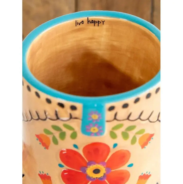Close up of a cowboy boot shaped ceramic mug interior with colourful floral detailing and “live happy” text