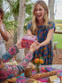 Smiling woman receiving floral cottage gift box at outdoor picnic table, unique gift packaging for special occasions Adventure Awaits