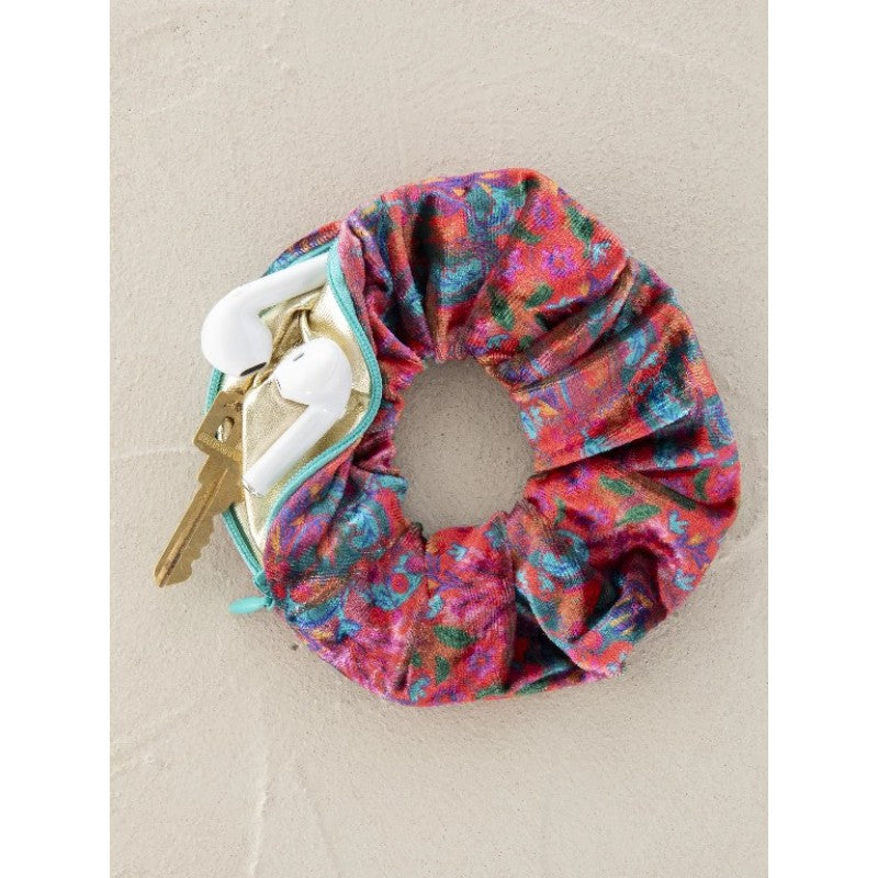 Floral scrunchie with hidden zip pocket holding keys and earbuds, stylish travel accessory for hands free convenience