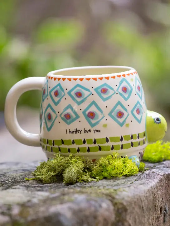 Turtle shaped ceramic mug with colourful geometric patterns and “I turtley love you” quote displayed outdoors