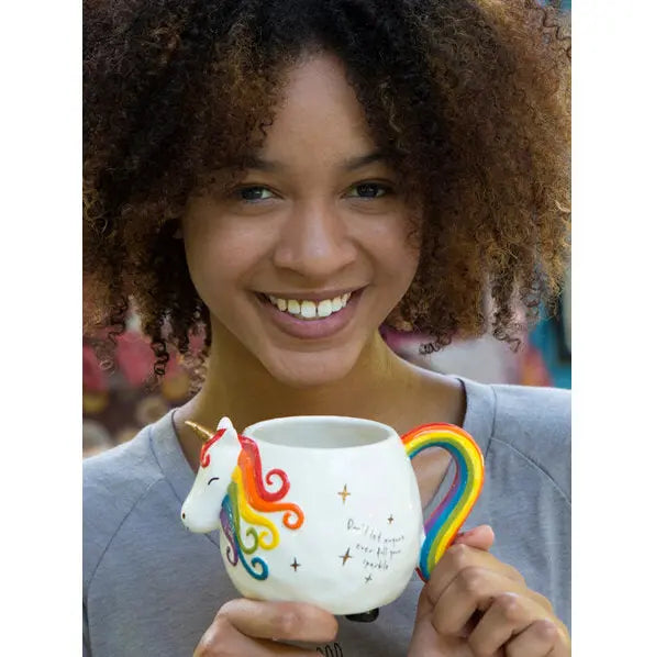 Smiling woman holding a unicorn shaped ceramic mug with rainbow handle and inspirational quote design