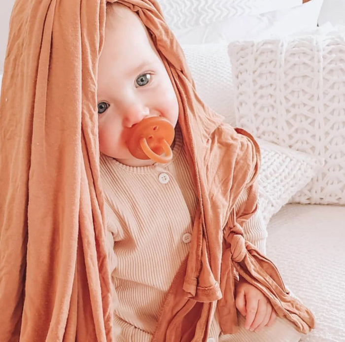 Baby with terracotta dummy and soft wrap blanket, soothing comfort for naps and travel Adventure Awaits