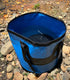 Blue Navigator Folding Bucket Buddy partially filled with creek water on a rocky bank - Adventure Awaits