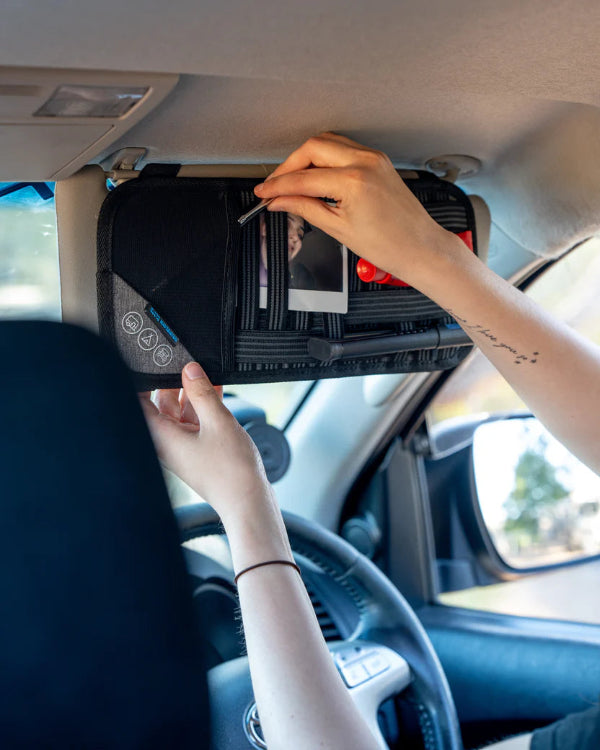 Person using a car visor organizer with multiple compartments.