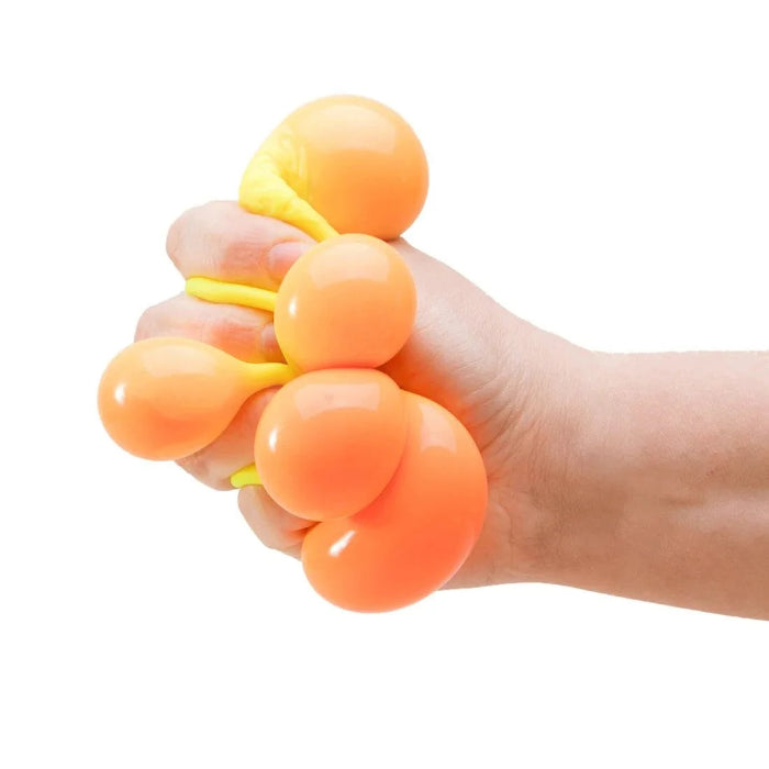 Hand squeezing an orange NeeDoh colour-change sensory cube as soft bubbles bulge out, Adventure Awaits