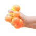 Hand squeezing an orange NeeDoh colour-change sensory cube as soft bubbles bulge out, Adventure Awaits
