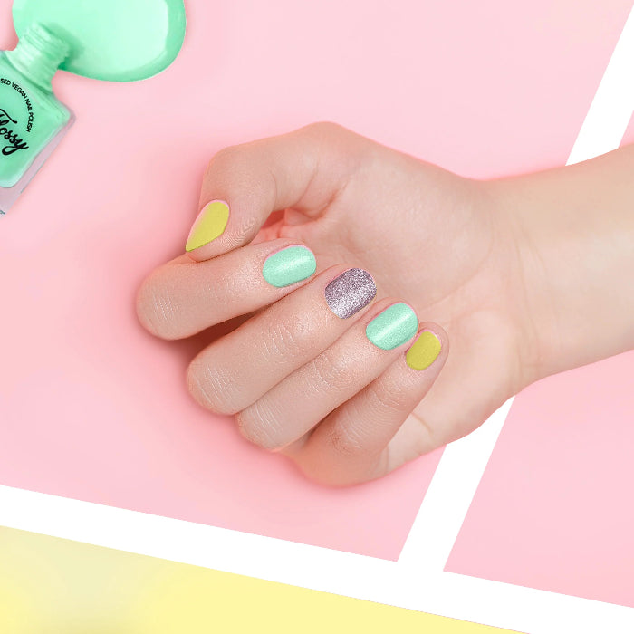 Child’s hand with pastel and glitter nail polish in green, yellow and silver, fun kids nail polish for dress ups Adventure Awaits
