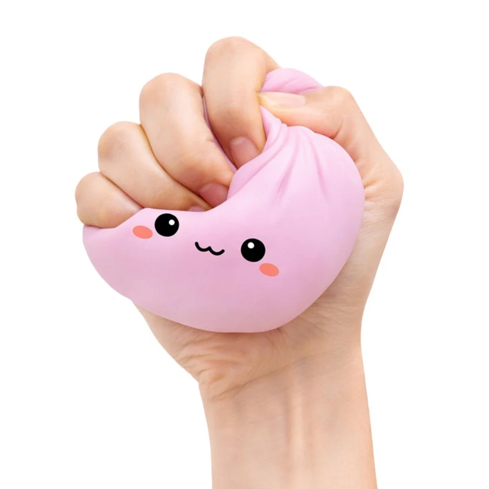 Hand holding a pink squishy lucky bao toy with a face design on a white background