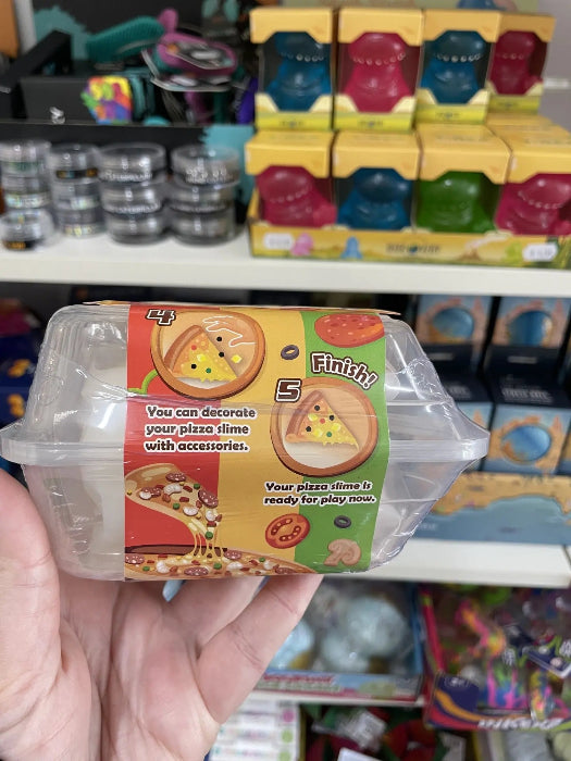 Hand holding Pizza Slime DIY pack showing decorate and finish steps on toy shop shelf — Adventure Awaits