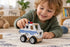 Child playing with Koala Dream white wooden police van on a playroom rug — Adventure Awaits