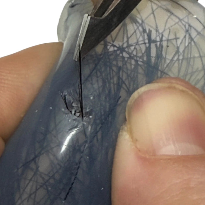 Person using scissors to cut a thin black line on a textured surface