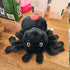 Red Back Black spider plush toy on a wooden surface with a box and books in the background