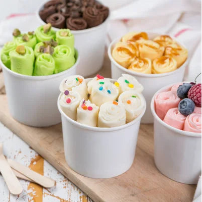 Colorful ice cream cones in white cups on a wooden board with a light background