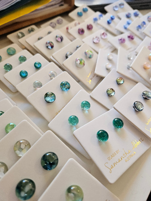 Display of gemstone earrings on white cards with visible brand name.