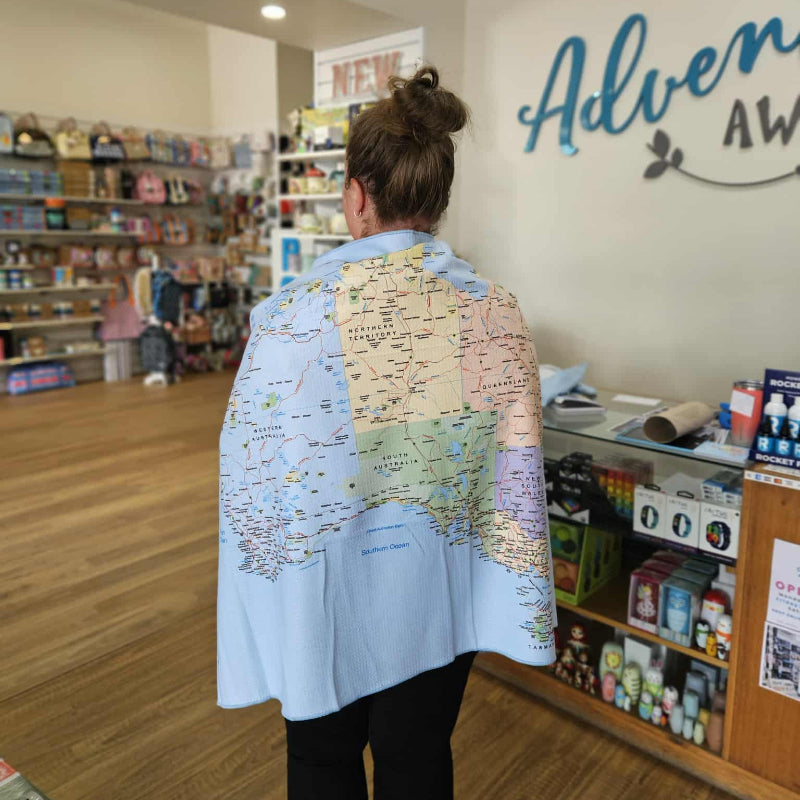 Person wearing a map-patterned shirt in a store with 'Adventure Awaits' sign.