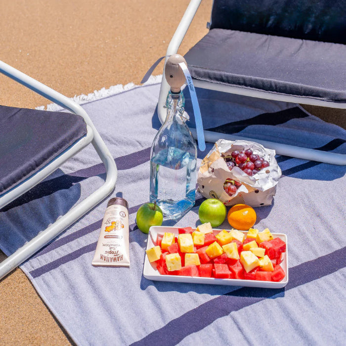 ShooAway rechargeable fly repeller on beach bottle beside fruit platter — Adventure Awaits
