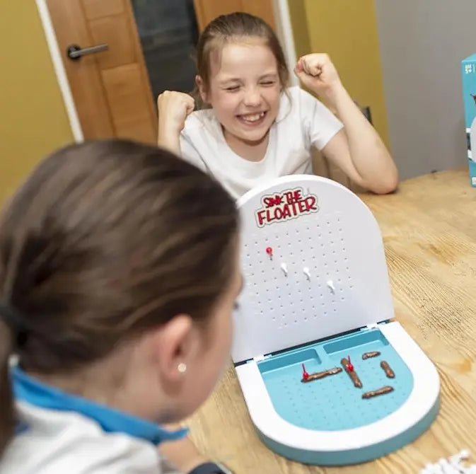 Kids laughing while playing Sink the Floater poop-themed tabletop game at a table — Adventure Awaits