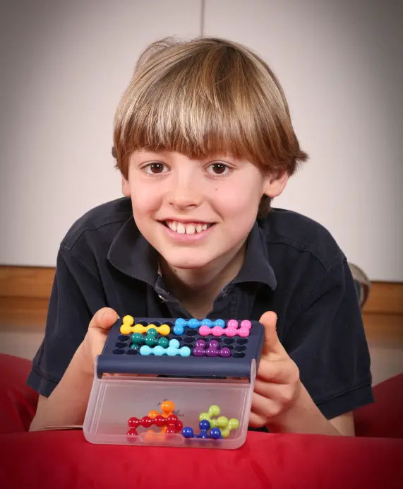 Child holding Smart Games IQ Fit logic game with colourful puzzle pieces — Adventure Awaits