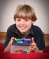 Child holding Smart Games IQ Fit logic game with colourful puzzle pieces — Adventure Awaits