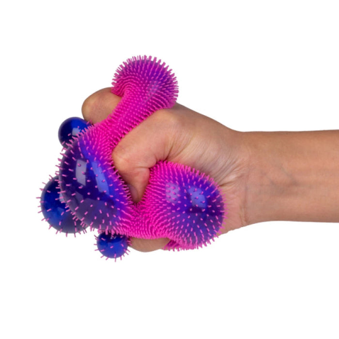 Hand squeezing a pink and purple spiky sensory stress toy with stretchy squishy texture
