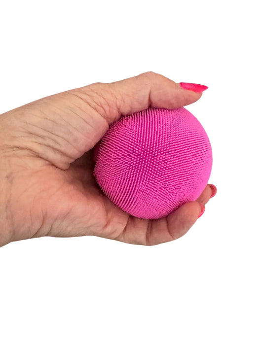 Hand holding a bright pink textured sensory stress ball with soft flexible spiky surface