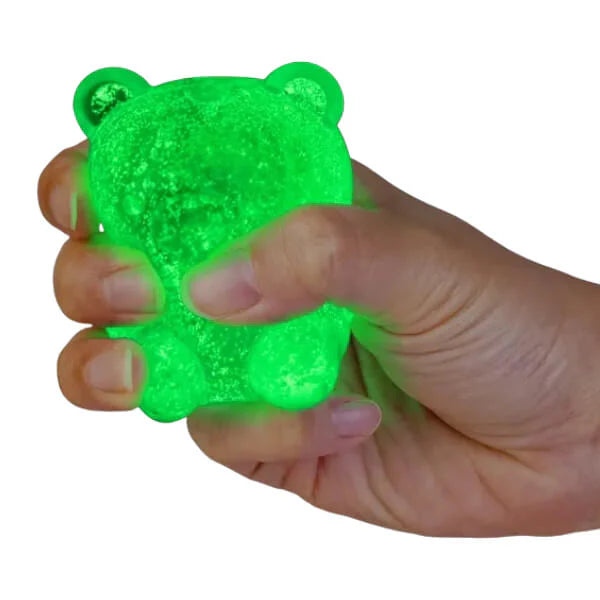 Hand squeezing green glow in the dark bear squishy toy with glittery finish — Adventure Awaits