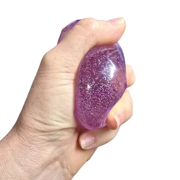 Hand squeezing purple diamond squishy toy with translucent glitter finish — Adventure Awaits