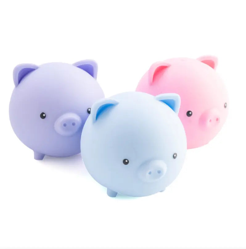 Trio of pastel pig shaped squishy sensory toys in purple, blue and pink with cute faces