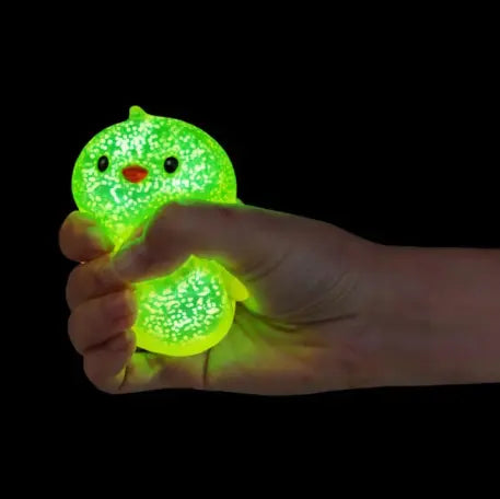 Hand squeezing green glow in the dark mini animal squishy toy against black background — Adventure Awaits