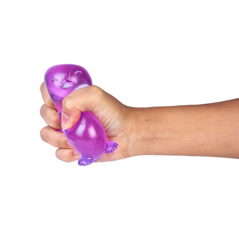 Hand squeezing Smooshos purple glitter glow in the dark penguin sensory toy  — Adventure Awaits