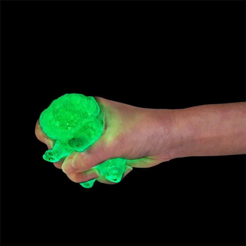 Hand squeezing green glow in the dark pug squishy toy against black background — Adventure Awaits