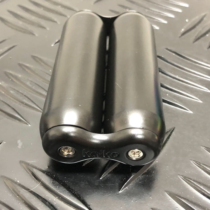 black Kaiko dual hand roller sensory tool with smooth metal rollers on a textured dark surface