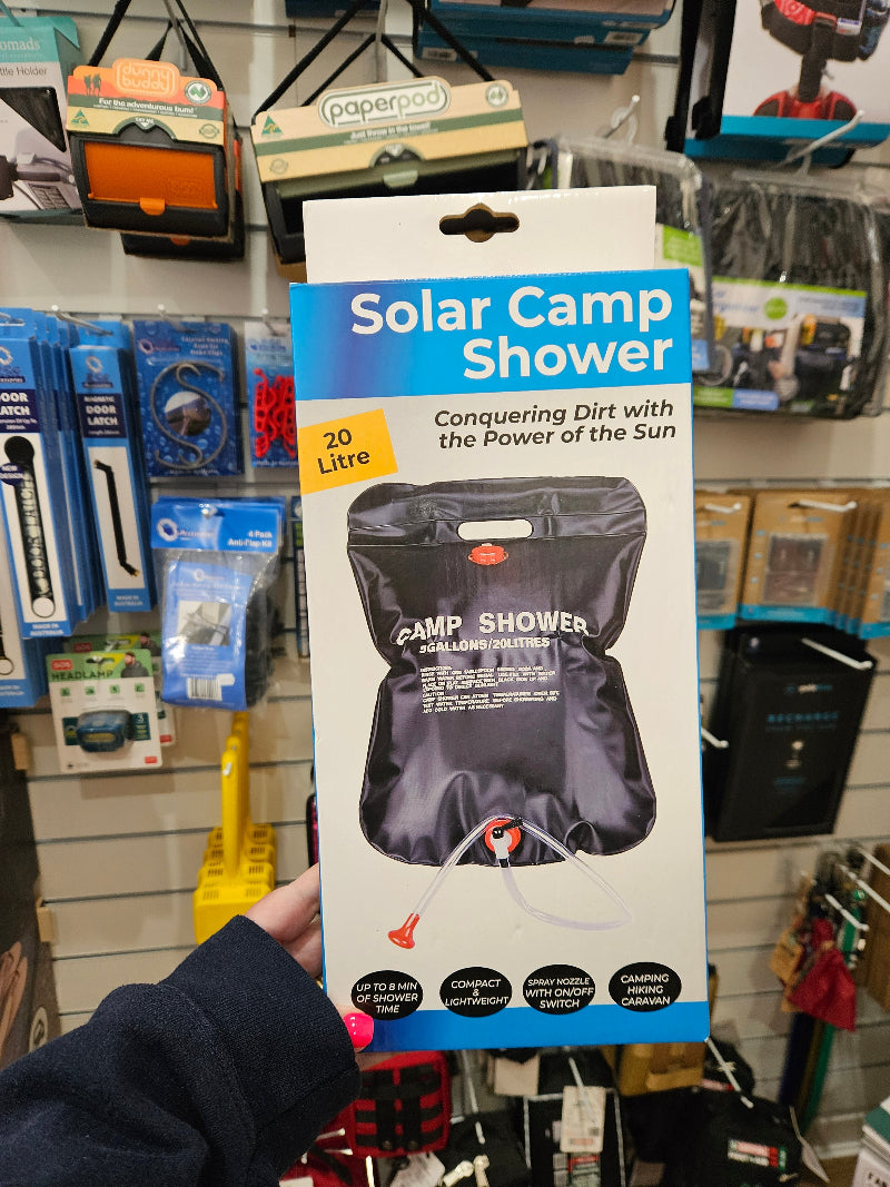 Solar Camp Shower packaging held in a store aisle with various items in the background