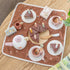 Wooden tea party set with cake, cups and teapot on a floral play mat — Adventure Awaits