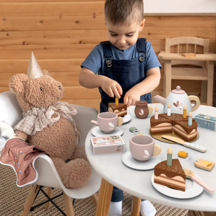 Child playing tea party with wooden cake, teapot and cups at a small table — Adventure Awaits