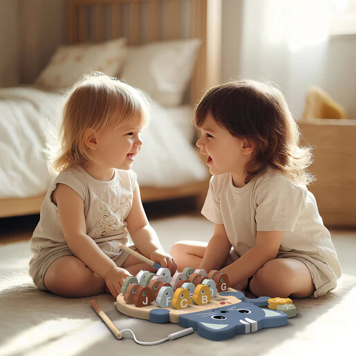 Two toddlers playing with wooden alphabet fishing game in sunny bedroom — Adventure Awaits