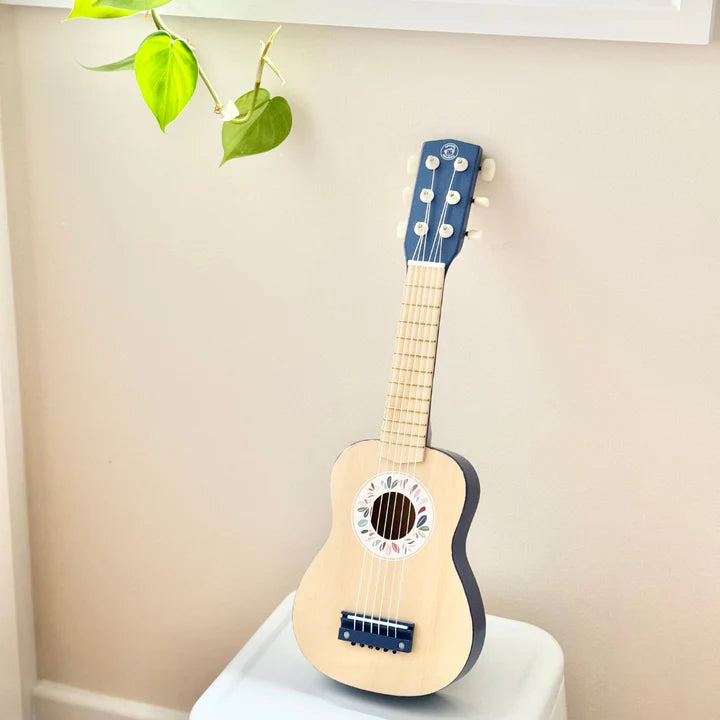 Blue wooden toy guitar with floral sound hole detail on nursery stool — Adventure Awaits
