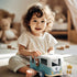 Toddler playing with blue wooden toy caravan in cosy nursery, kids travel toy — Adventure Awaits