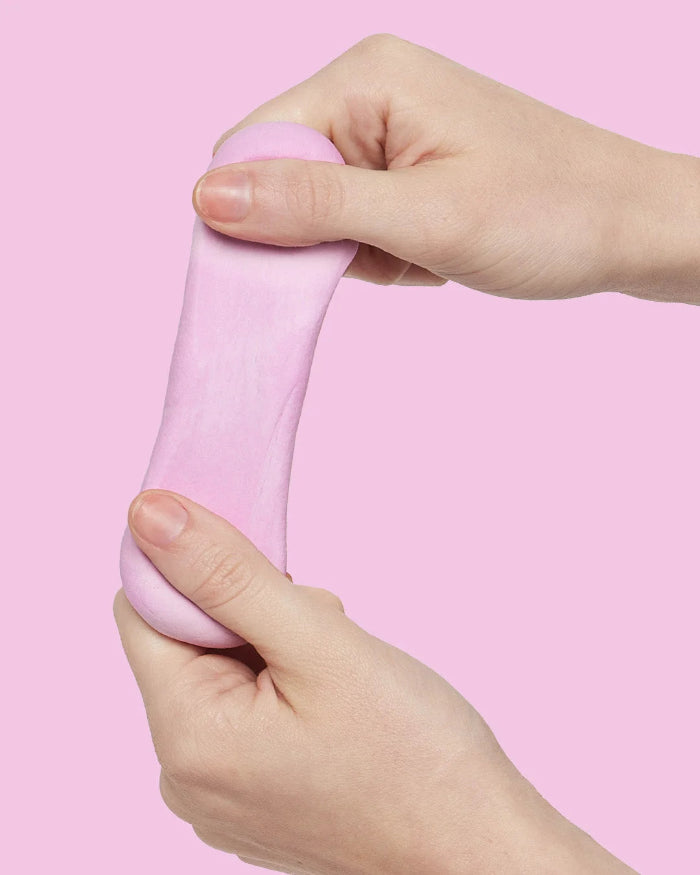 Hands stretching soft pink SPEKS Blur calming focus putty against a pink background — Adventure Awaits