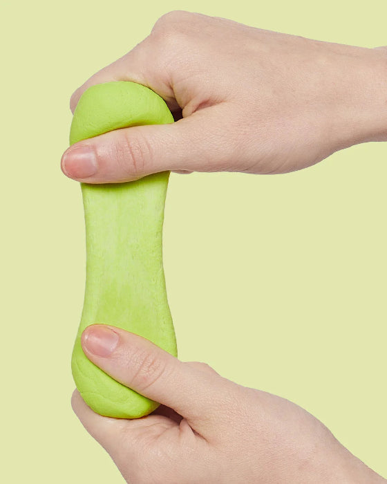 Hands stretching lime green SPEKS Blur calming focus putty against a pale green background — Adventure Awaits
