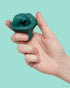 Hand holding dark teal SPEKS Blur calming focus putty against a mint background — Adventure Awaits