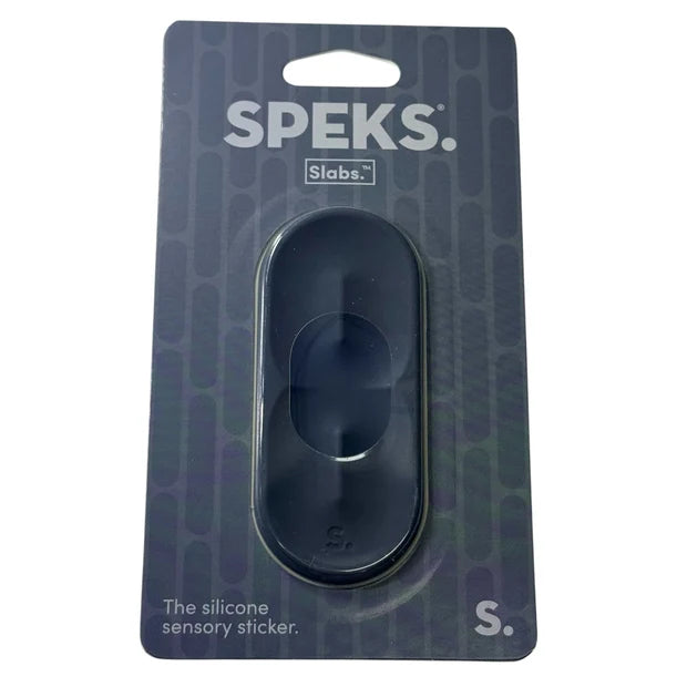 Speks Slabs S silicone sensory sticker in its original blister packaging, featuring a dark blue-gray oval-shaped sticker on a dark patterned backing card.