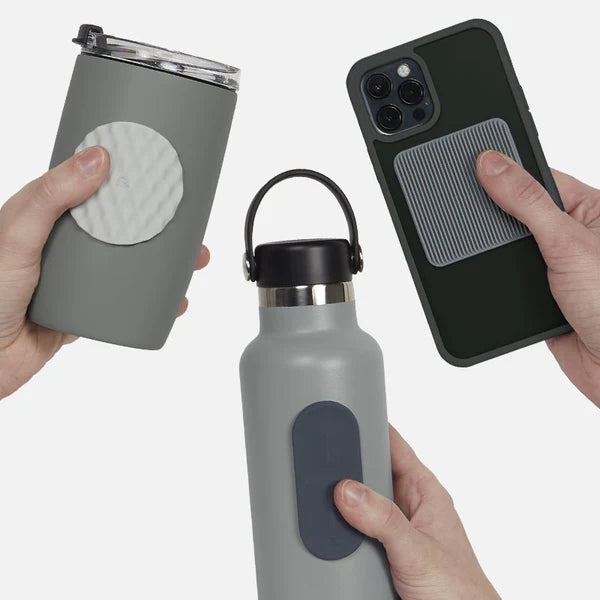 Hands holding a grey tumbler, water bottle, and phone case with textured silicone fidget sticker by speks