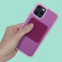 Hand holding a pink phone case with mesh fidget sticker against a teal background