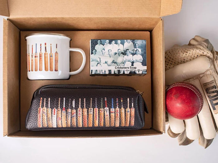 The Cricketers Gift set with cricket bat enamel mug, cricketers soap and matching wash bag beside cricket gloves and red ball — Adventure Awaits