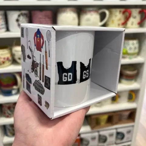 Vintage netball bib mug in illustrated Sporting Nation gift box, held in a shop — Adventure Awaits