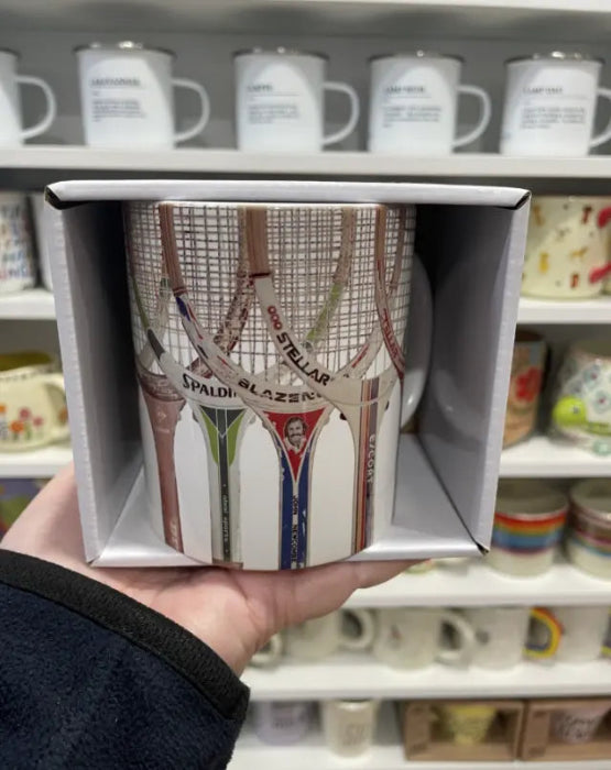 Vintage tennis racquet mug in gift box, held in front of a shop display — Adventure Awaits