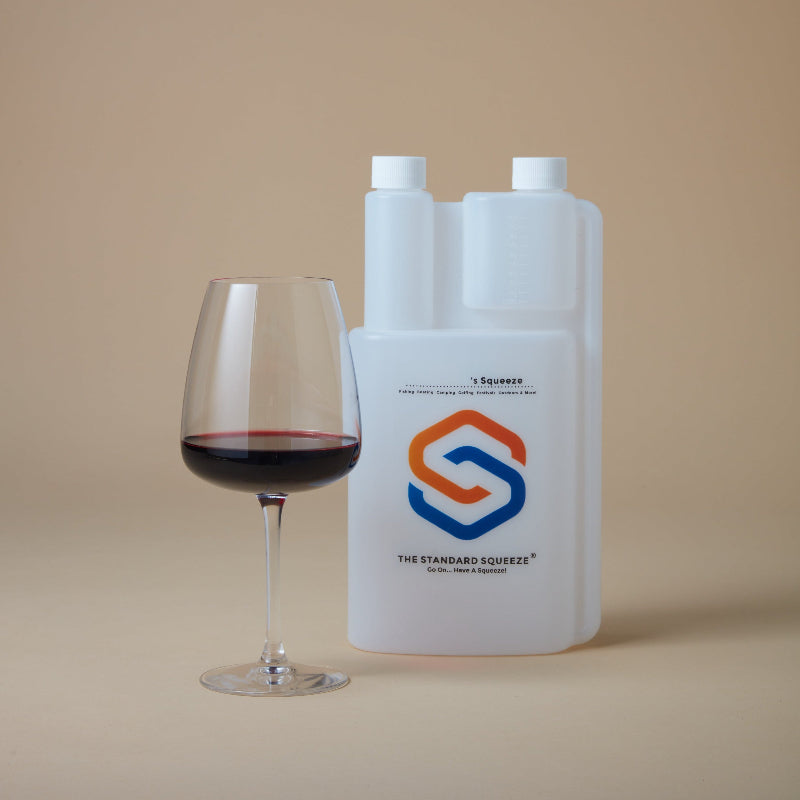 Standard Squeeze Bottle beside a glass of red wine on a neutral background — Adventure Awaits