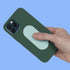 Hand holding a green phone case with a textured speks slabs silicone fidget sticker on a blue background